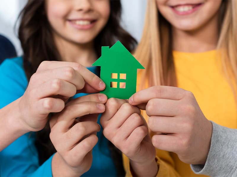 Two young people holding a paper house cut-out, symbolising the Youth Housing Project's mission Two young people holding a paper house cut-out, symbolising the Youth Housing Project's mission